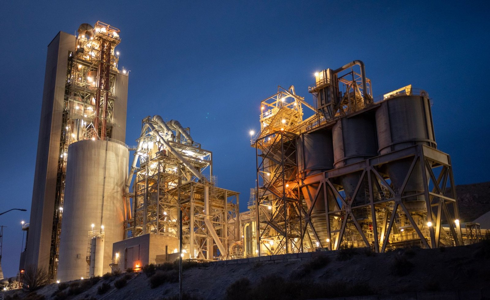 An illuminated industrial plant shows the scale of connected process equipment.