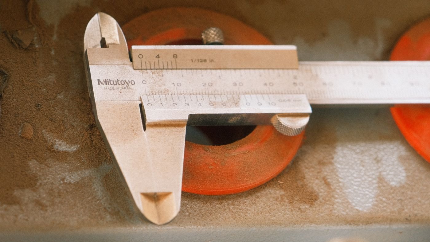 A caliper on a metal surface illustrates dimensional inspection tools.